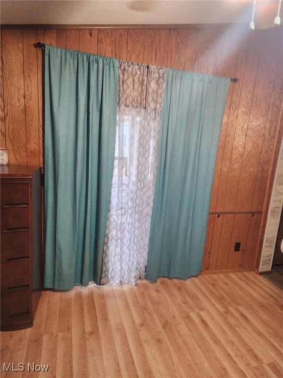 unfurnished bedroom featuring light wood-type flooring and wooden walls