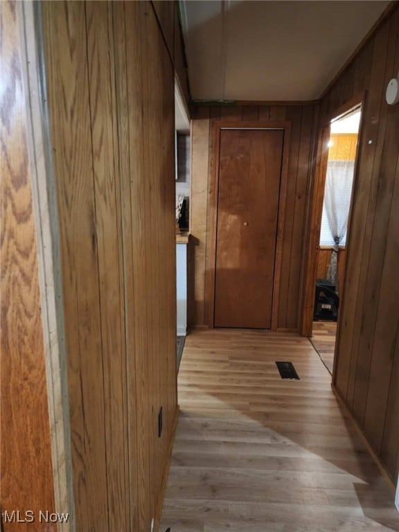 hallway with light hardwood / wood-style floors and wood walls