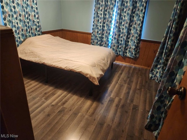 bedroom with wood walls and dark wood-type flooring