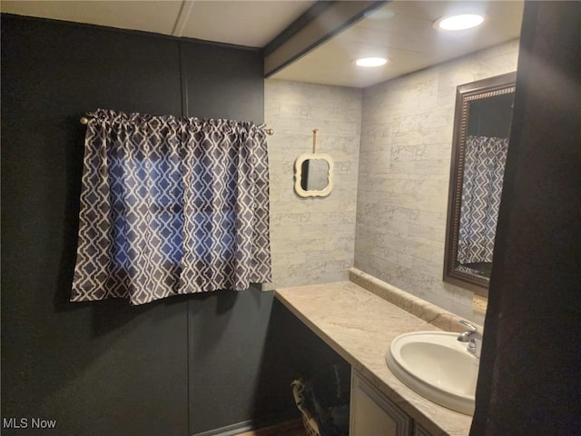 bathroom with vanity and tile walls