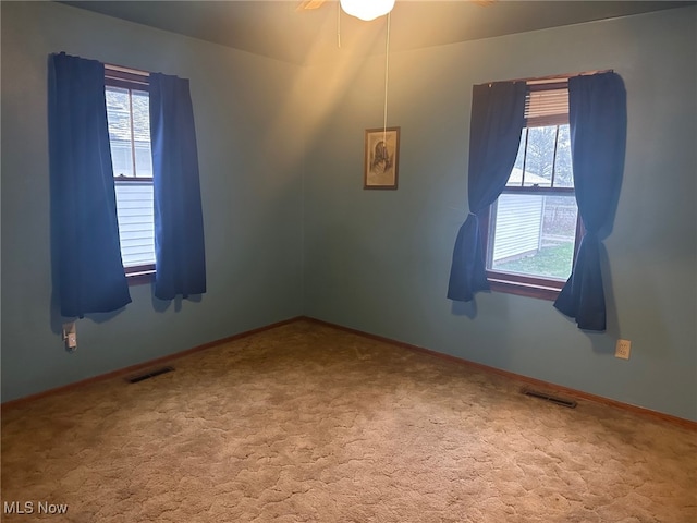 carpeted spare room featuring ceiling fan and a healthy amount of sunlight