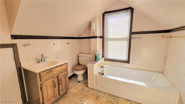 bathroom with a bath, vaulted ceiling, toilet, vanity, and tile walls