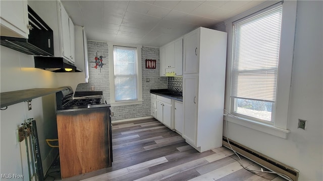 kitchen featuring white cabinets, a baseboard radiator, and brick wall