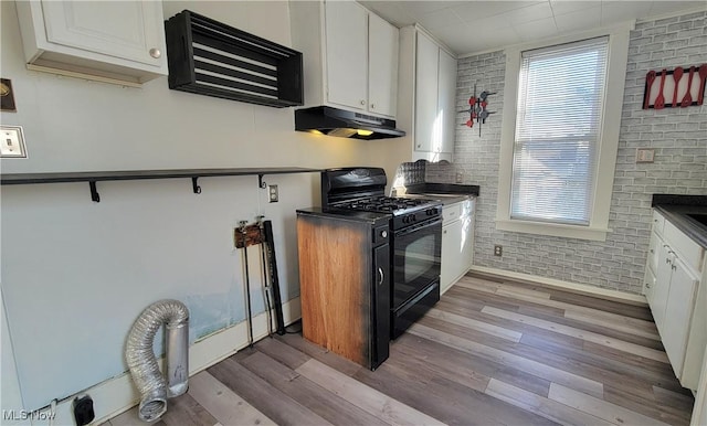 119 Euclid Pl, Marietta, OH 45750 - kitchen featuring black range with gas cooktop, under cabinet range hood, healthy amount of natural light, white cabinets, and brick wall