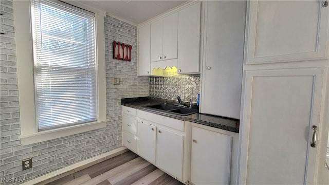 kitchen featuring white cabinetry, sink, ornamental molding, and light wood-type flooring