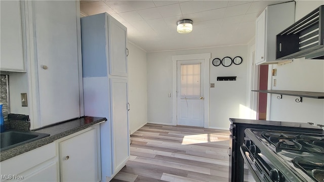 kitchen featuring white cabinetry, light hardwood / wood-style flooring, black gas range oven, and ornamental molding