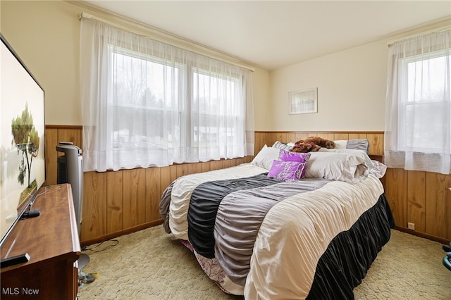 bedroom featuring light colored carpet and wooden walls