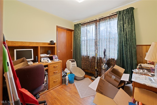 office area with light hardwood / wood-style flooring and wooden walls