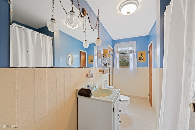 bathroom with vanity, toilet, and tile walls