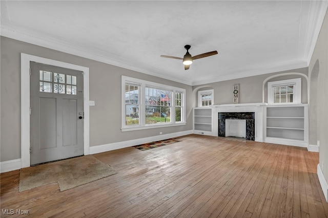 unfurnished living room with wood-type flooring, ceiling fan, ornamental molding, and a premium fireplace