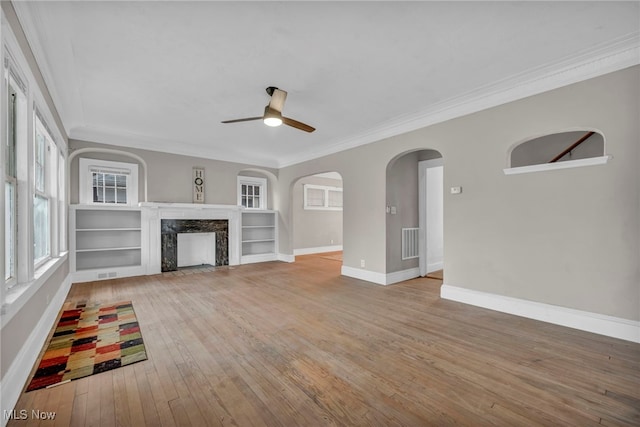 unfurnished living room with light wood-type flooring, ceiling fan, crown molding, and a premium fireplace