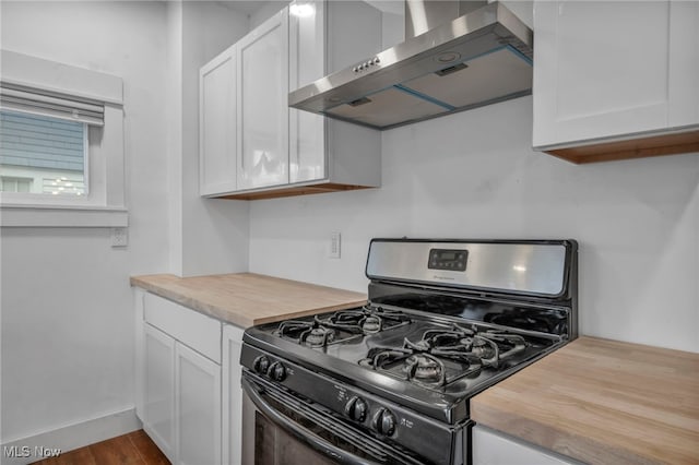 kitchen with wall chimney exhaust hood, black range with gas stovetop, wooden counters, white cabinets, and hardwood / wood-style flooring