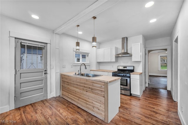 kitchen with dark hardwood / wood-style flooring, wall chimney exhaust hood, sink, white cabinets, and stainless steel gas stove