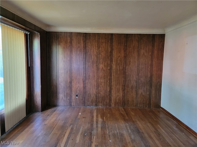 unfurnished room with dark hardwood / wood-style floors and wood walls