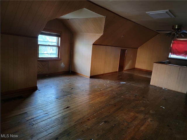 bonus room with wooden walls, dark wood-type flooring, and lofted ceiling