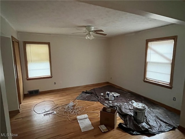 empty room featuring light hardwood / wood-style floors, ceiling fan, and a healthy amount of sunlight