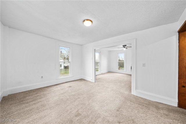 empty room with carpet flooring, ceiling fan, a textured ceiling, and a wealth of natural light