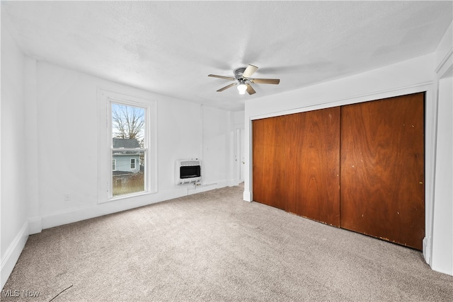 unfurnished bedroom featuring a closet, carpet floors, heating unit, and ceiling fan