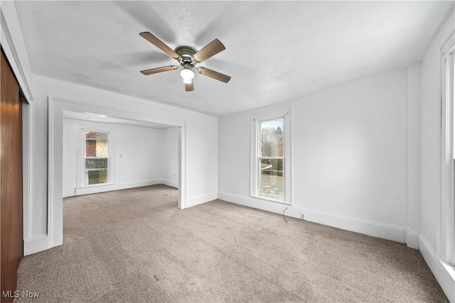 unfurnished room with light colored carpet, a healthy amount of sunlight, and a textured ceiling