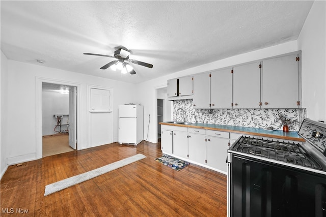 kitchen featuring white fridge, black stove, a textured ceiling, and dark wood-type flooring