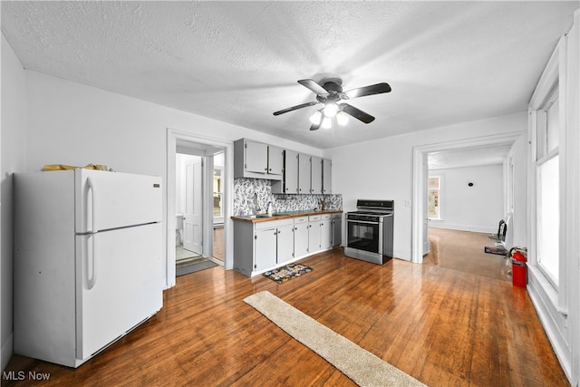 kitchen featuring dark wood-type flooring, stainless steel stove, white fridge, and a textured ceiling