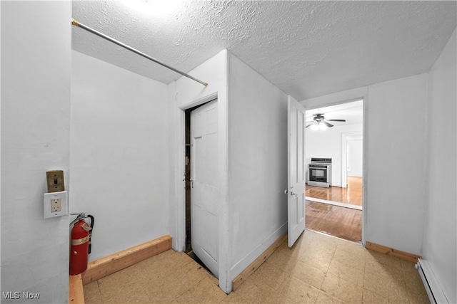 hall with a textured ceiling, a baseboard radiator, and light hardwood / wood-style floors