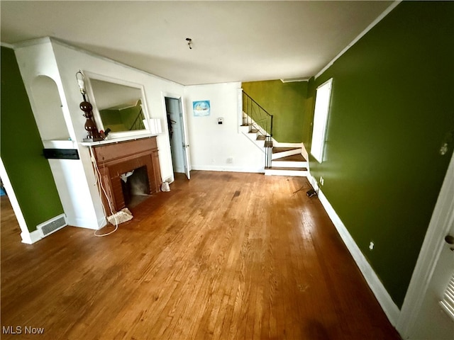 unfurnished living room featuring hardwood / wood-style floors and ornamental molding