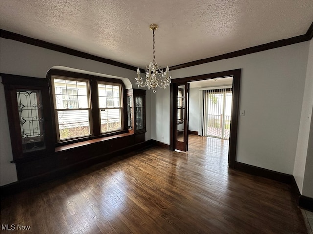 unfurnished dining area featuring a chandelier, ornamental molding, a textured ceiling, and dark wood-type flooring