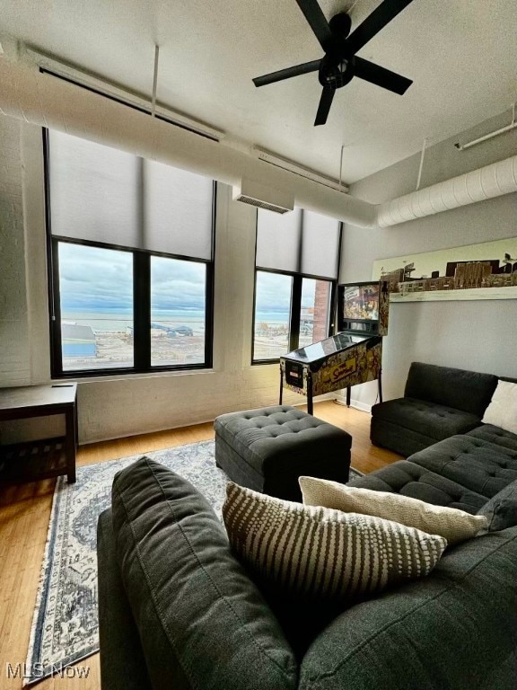 living room with a textured ceiling, light wood-type flooring, and ceiling fan