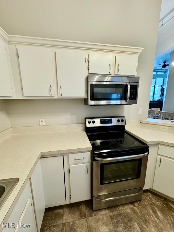 kitchen with white cabinets, appliances with stainless steel finishes, and dark wood-type flooring