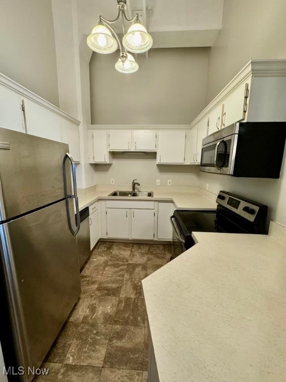 kitchen featuring white cabinets, decorative light fixtures, stainless steel appliances, and sink