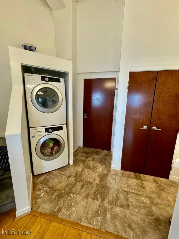 laundry room with wood-type flooring and stacked washing maching and dryer