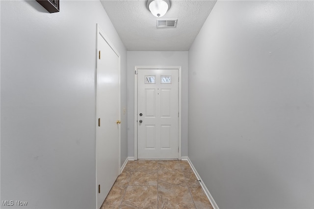 doorway to outside with light tile patterned floors and a textured ceiling