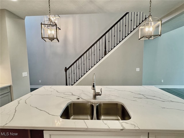 kitchen featuring light stone countertops, pendant lighting, and sink