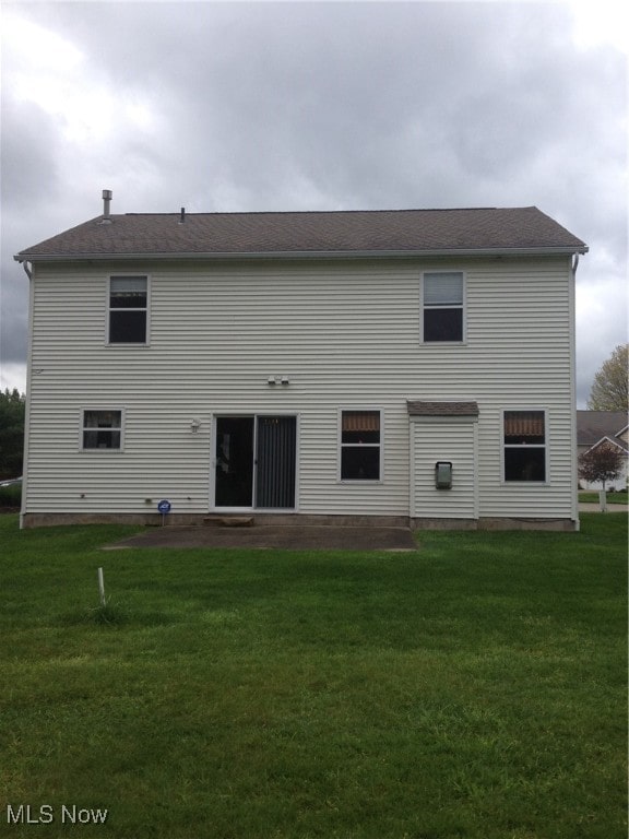 back of house featuring a lawn and a patio