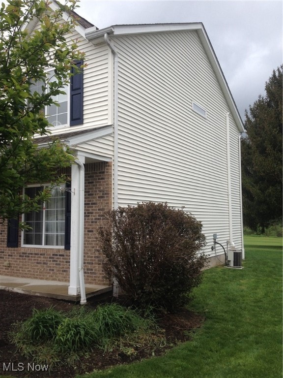 view of side of home with a lawn and central AC