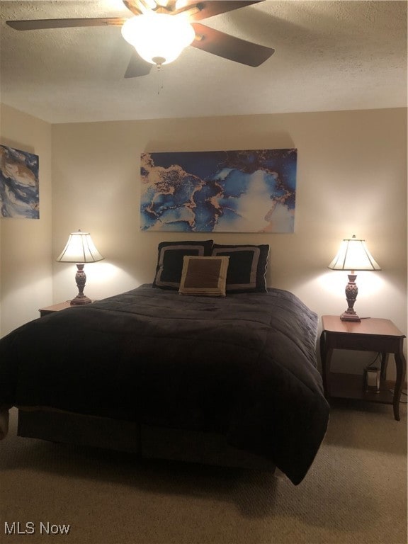 bedroom with ceiling fan, carpet, and a textured ceiling