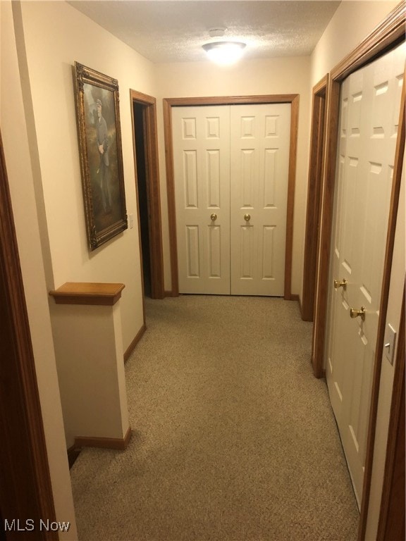 hallway featuring a textured ceiling and light colored carpet