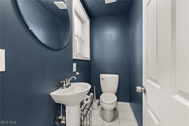 bathroom with tile patterned flooring, a textured ceiling, toilet, and sink