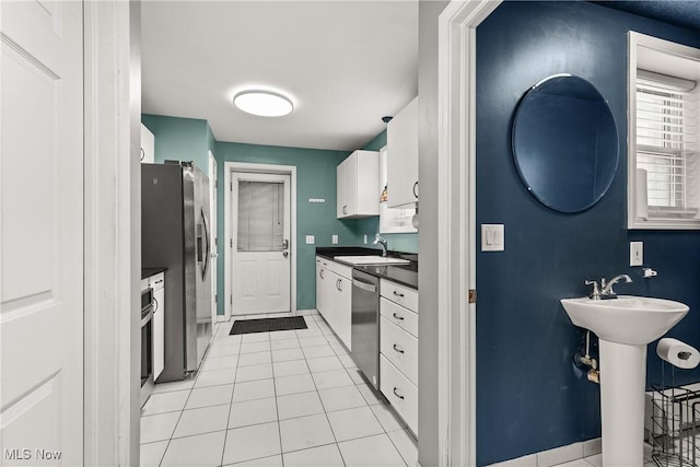 kitchen featuring white cabinetry, sink, light tile patterned floors, and appliances with stainless steel finishes