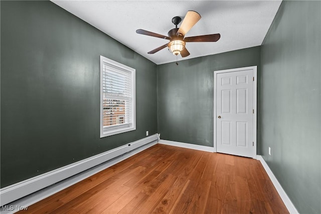 spare room with hardwood / wood-style floors, baseboard heating, and ceiling fan