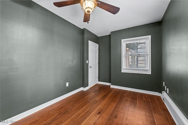 unfurnished room with ceiling fan, dark wood-type flooring, and a baseboard radiator