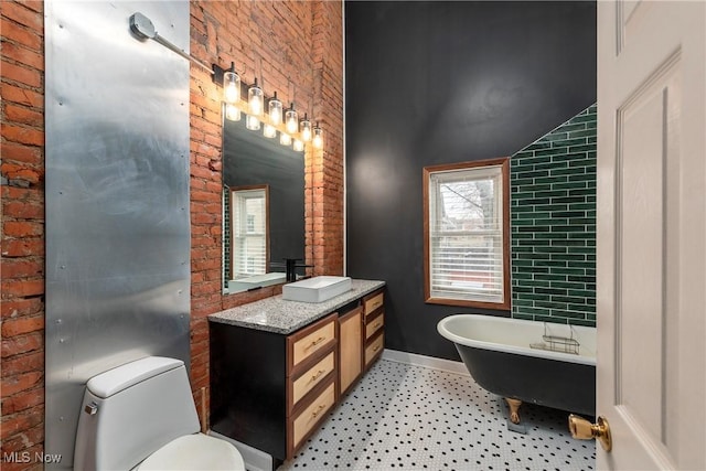 bathroom featuring a tub, brick wall, vanity, toilet, and lofted ceiling