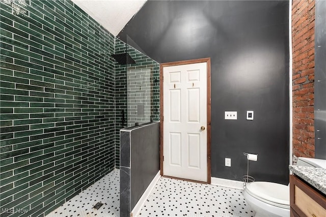 bathroom with a tile shower, vanity, and toilet