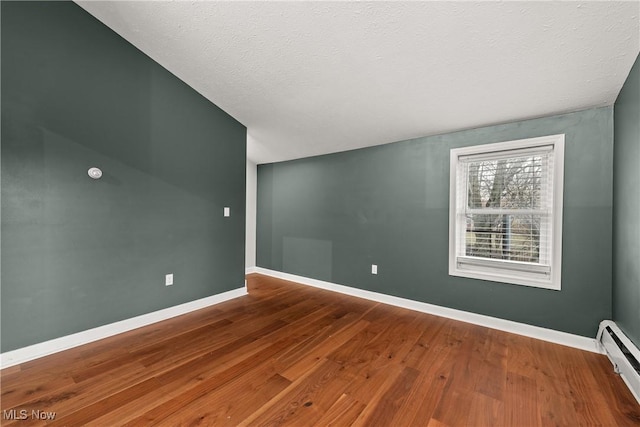 spare room with baseboard heating, wood-type flooring, and a textured ceiling