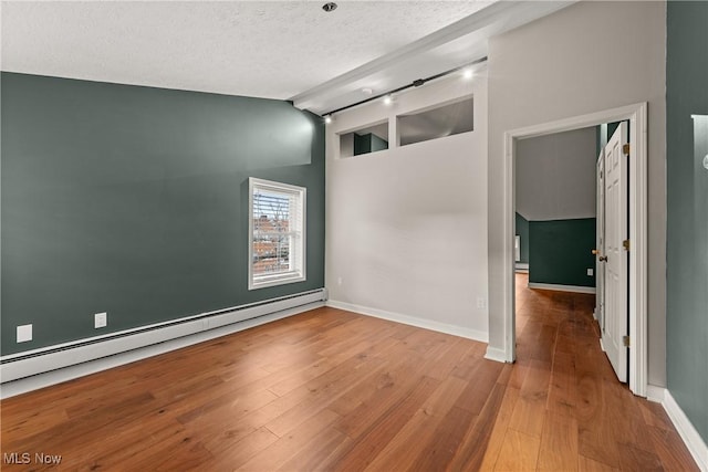 unfurnished room featuring lofted ceiling, hardwood / wood-style floors, a textured ceiling, and a baseboard heating unit