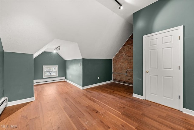 bonus room featuring brick wall, a baseboard radiator, lofted ceiling, and hardwood / wood-style flooring