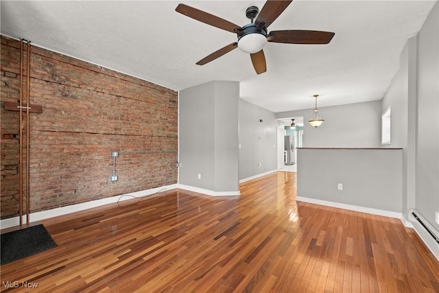 unfurnished living room with ceiling fan, wood-type flooring, brick wall, and a baseboard heating unit