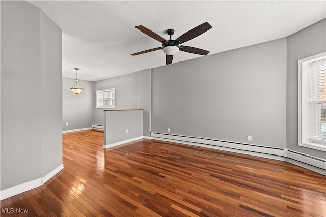 empty room featuring hardwood / wood-style floors, plenty of natural light, ceiling fan, and a baseboard radiator