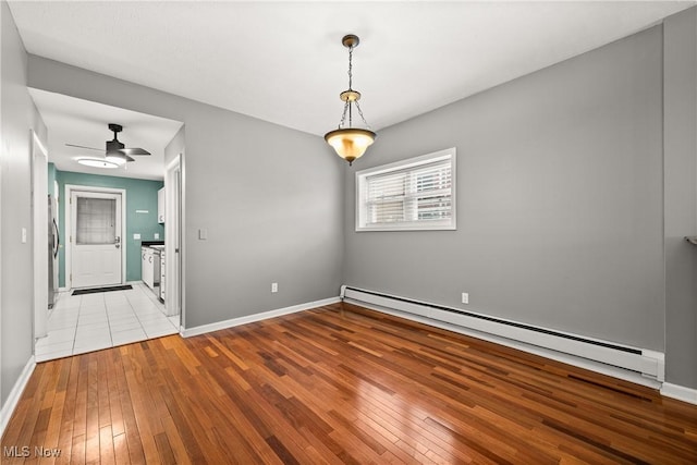 spare room with ceiling fan, a baseboard radiator, and light hardwood / wood-style floors